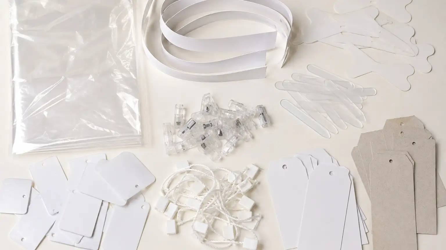 Shirt packing items: a folded clear cover, coiled collar bands, collar support butterflies, clear collar stays, shirt clips and blank tags.